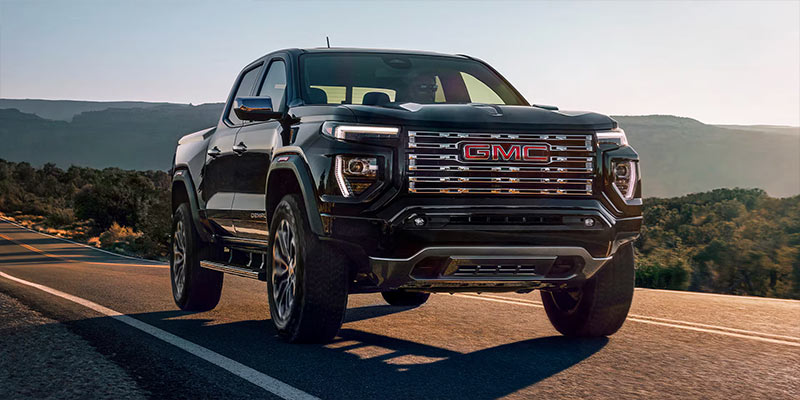 a black 2025 GMC Canyon driving down a paved road.