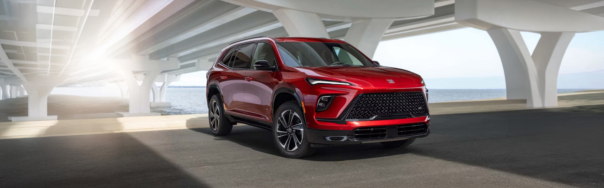 2026 Buick Enclave red SUV parked under a modern structure in Mandan, ND