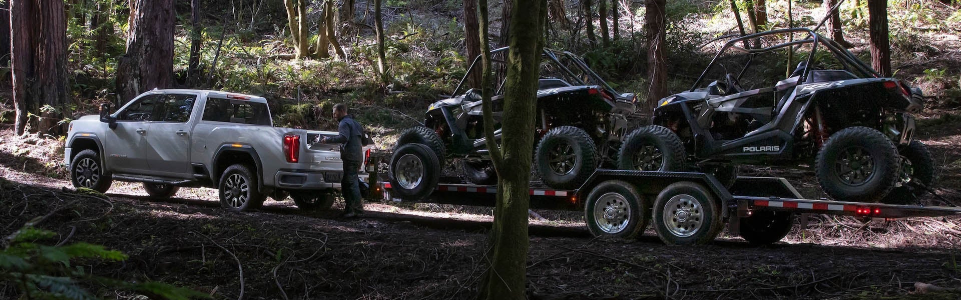 White GMC Sierra 1500 pulling two other vehicles