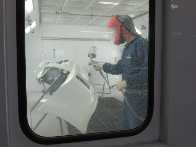Person wearing a mask and spray painting a car white